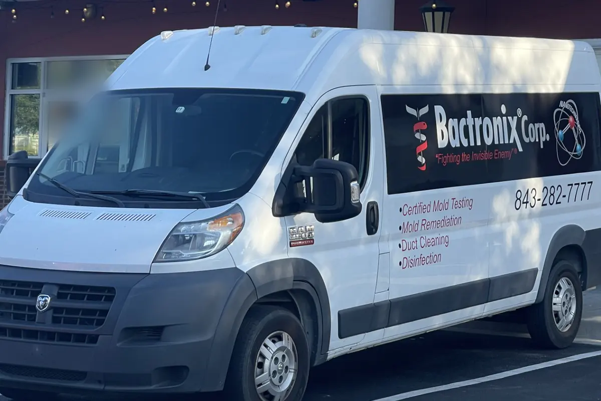 A Bactronix service van lettered with the company name, its services and its phone number, parked outside a commercial building