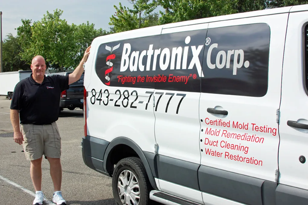 Greg Busang standing beside his Bactronix van, the company name and 843-282-7777 lettered along the side